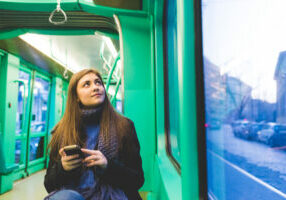 young woman outdoor using smart phone hand hold travelling public transport - technology, commuter, internet concept